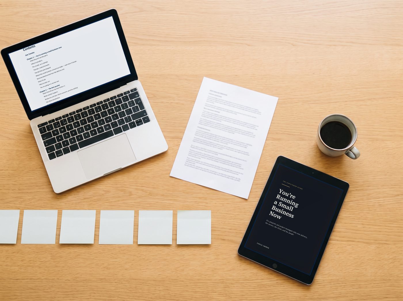 The kit on a desk: the guide's contents on a laptop, the cover on a tablet, a printed one-page brief and a coffee.